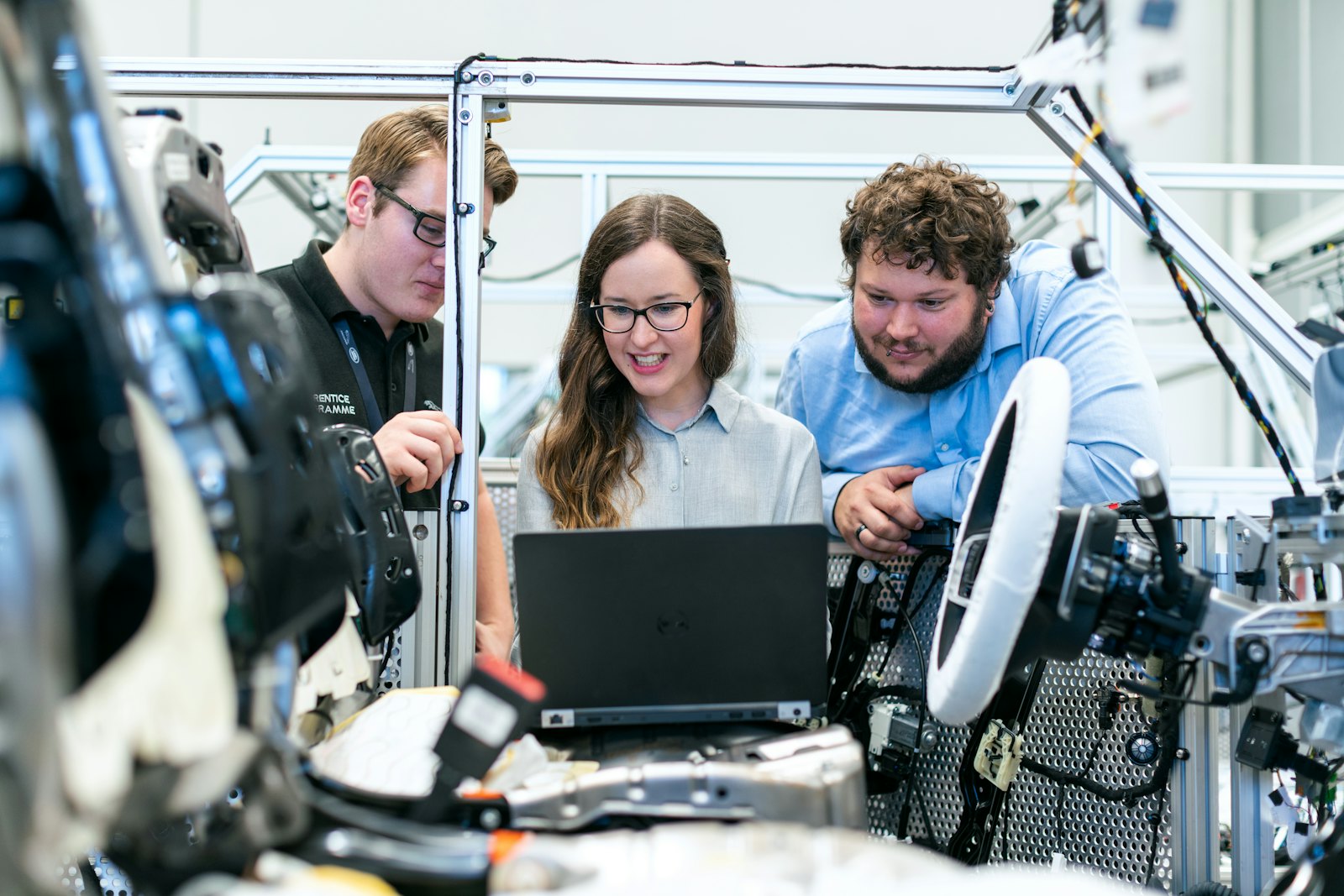 Ingenjörer arbetar tillsammans vid en robotcell med en bärbar dator